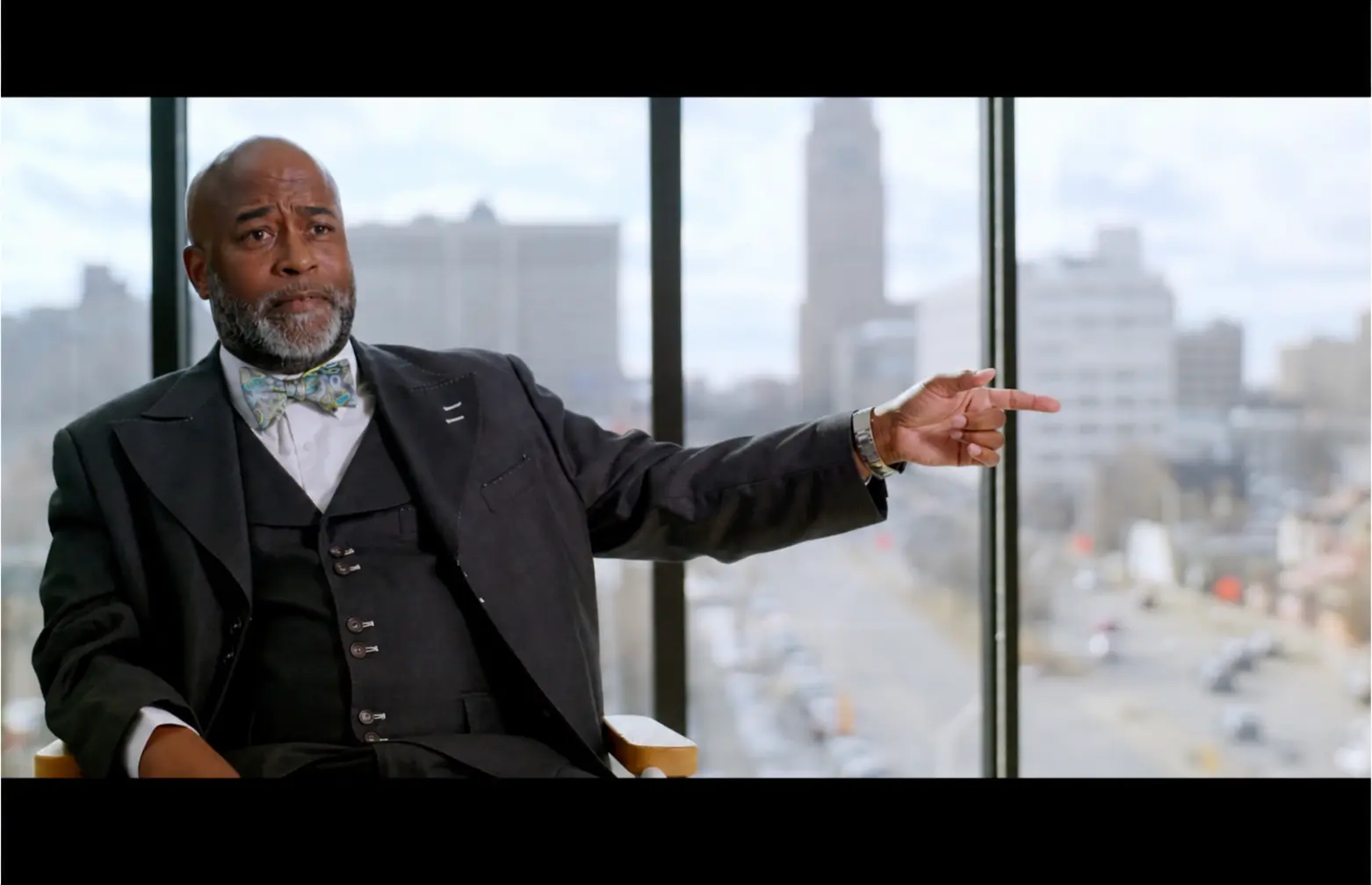 An educator gestures toward the Detroit skyline during an interview.