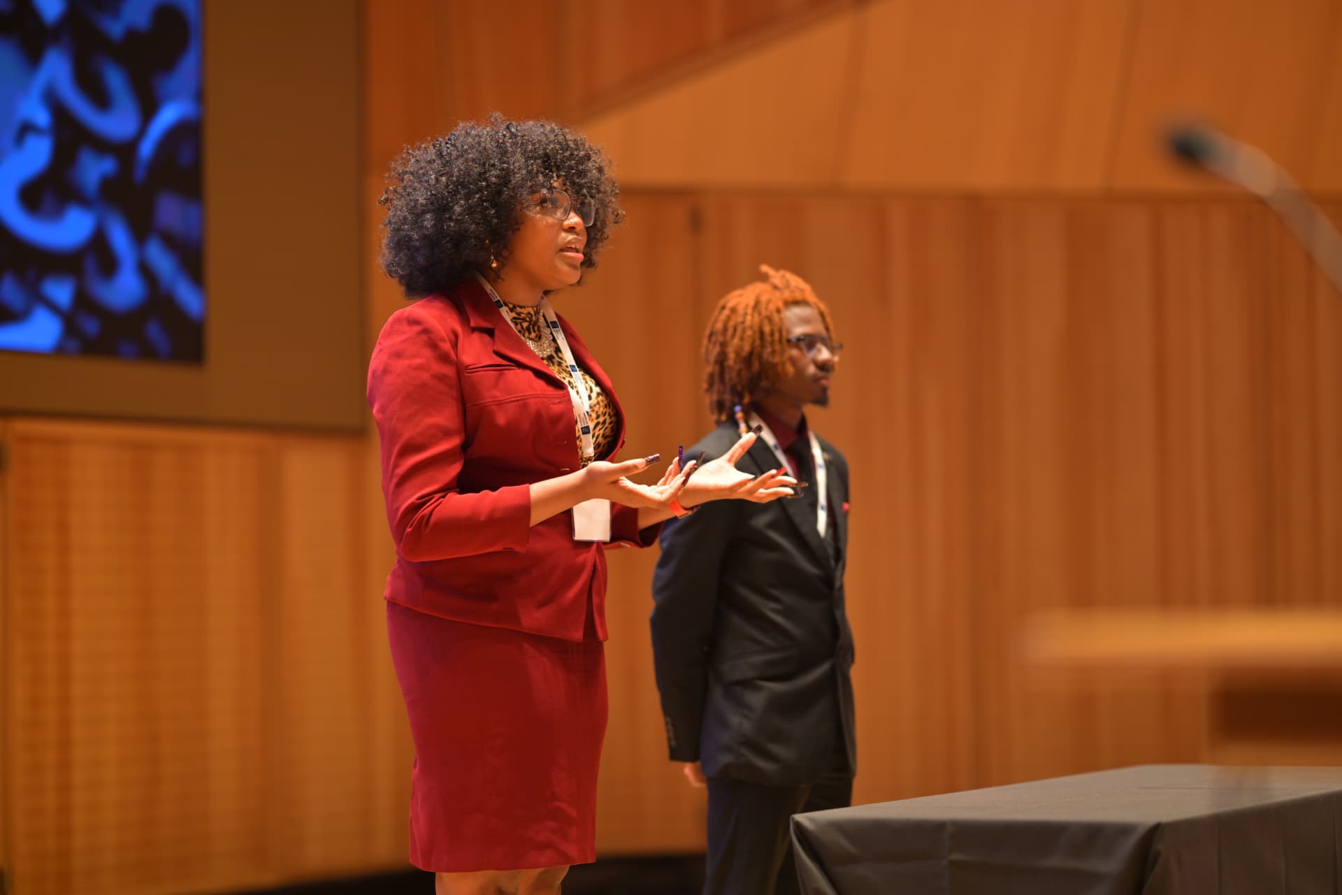 Two speakers present on stage at a community event.